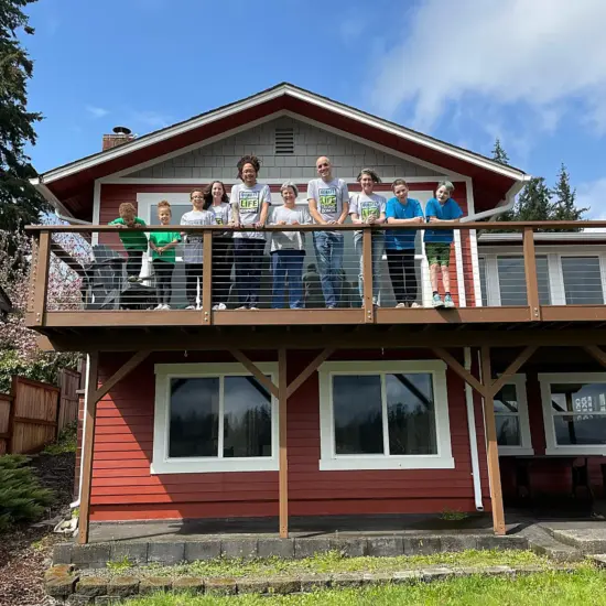The May and Butler families pose together on the deck of a red cabin.