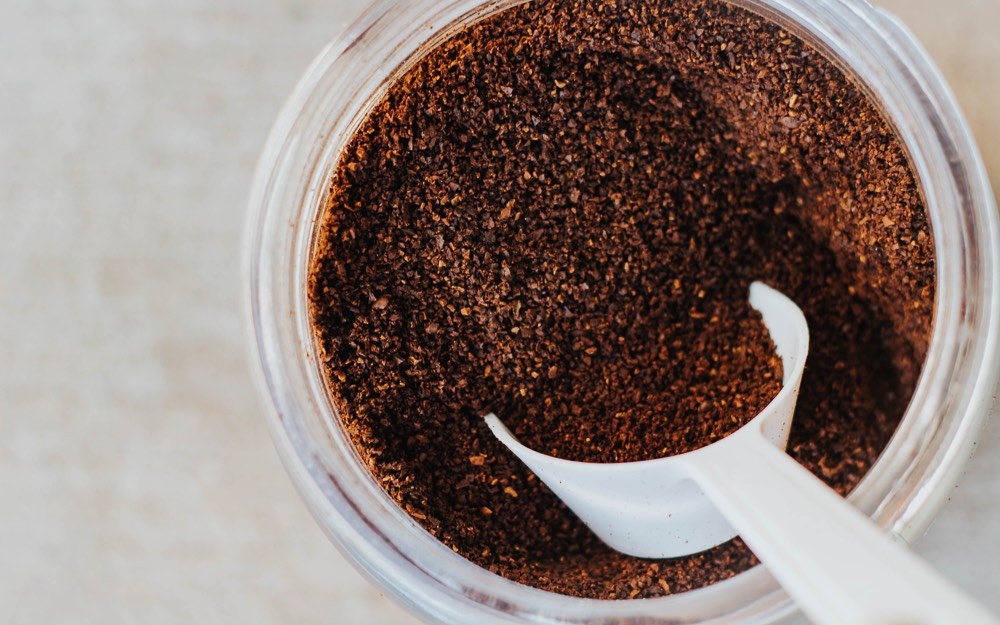 Ground coffee with a scoop in a container.