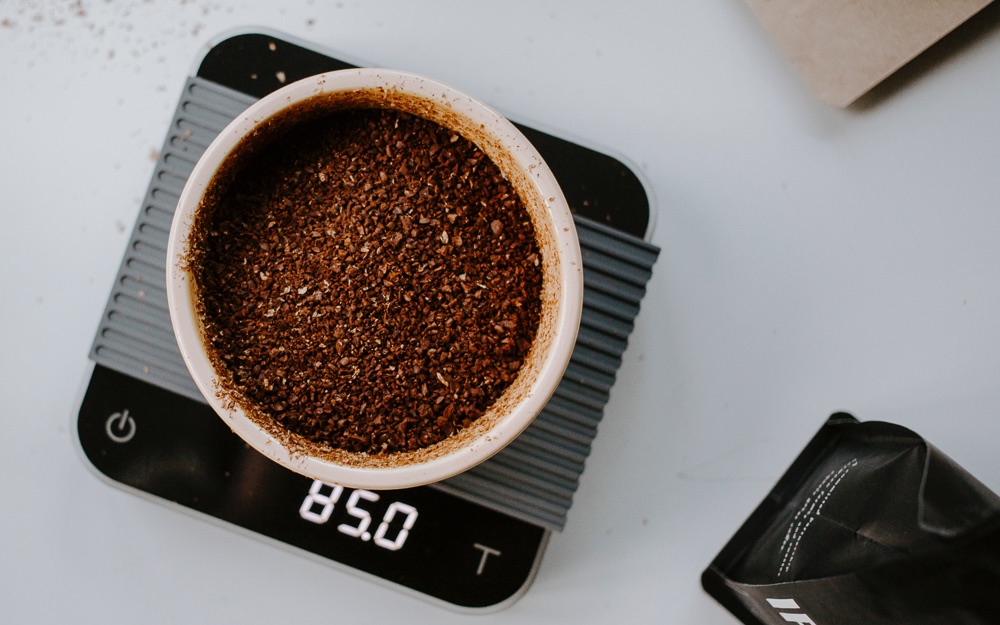 Ground coffee being weighed on a scale.