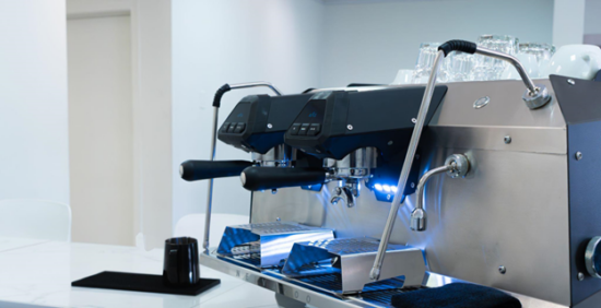 Side view of espresso machine in gunmetal coloring with blue light and black accents.