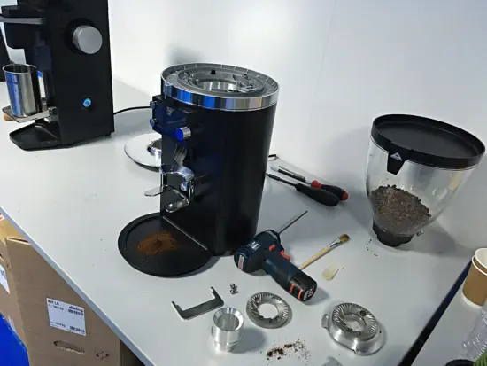 The top portion of a grinder is disassmbled with parts on the table.