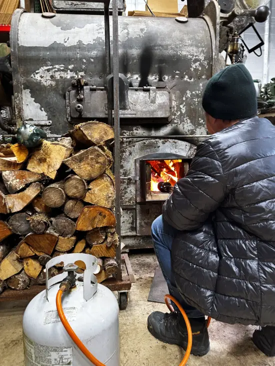 A man pokes the fire inside the roaster.