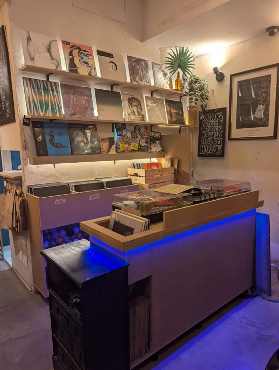 The vinyls shop inside Blend. Two record players backlit with blue light sit in front of shelves and bins of vinyl for sale.