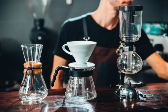 A barista behind a bar with three brewing methods.