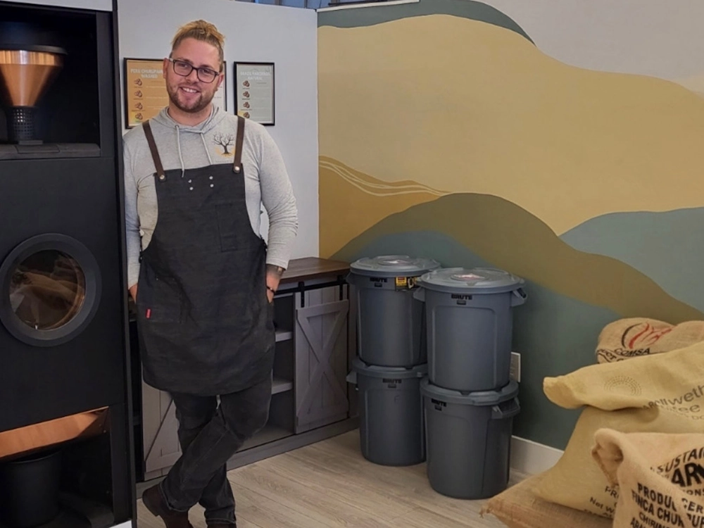 Donovan Albert stands next to a Bellwether Shop Roaster at Anchor & Tree micro coffee roastery.