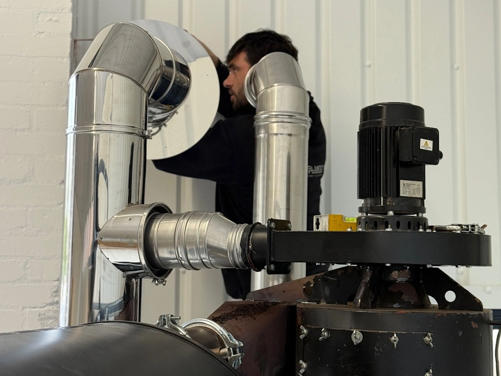 A CRS team member fixes a roaster ventilation system.