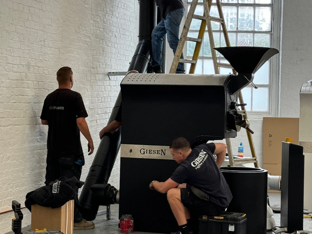 People setting up a Giesen coffee roaster.